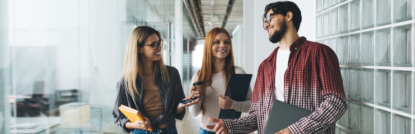 Trois collègues qui discutent dans un couloir, pour le dialogue social