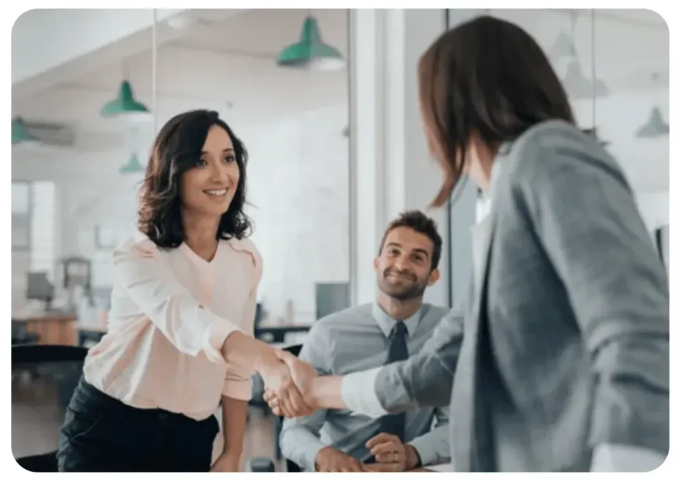 Poignée de main entre une dirigeante et un collaborateur dans un bureau lumineux